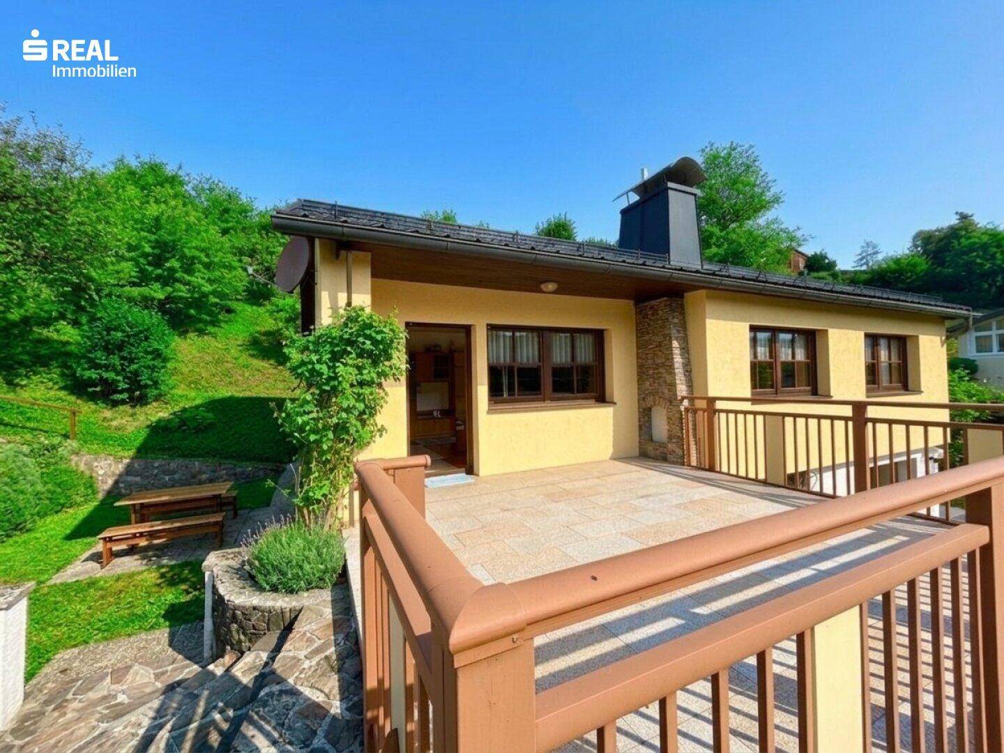 Blick von der Terrasse auf das Haus mit Eingangsbereich und angrenzendem kleinen Garten.
