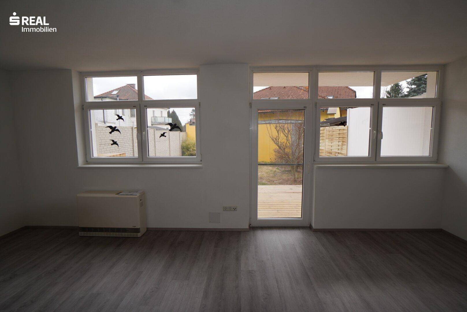 Helles Wohnzimmer mit großen Fenstern und Zugang zur Holzterrasse.