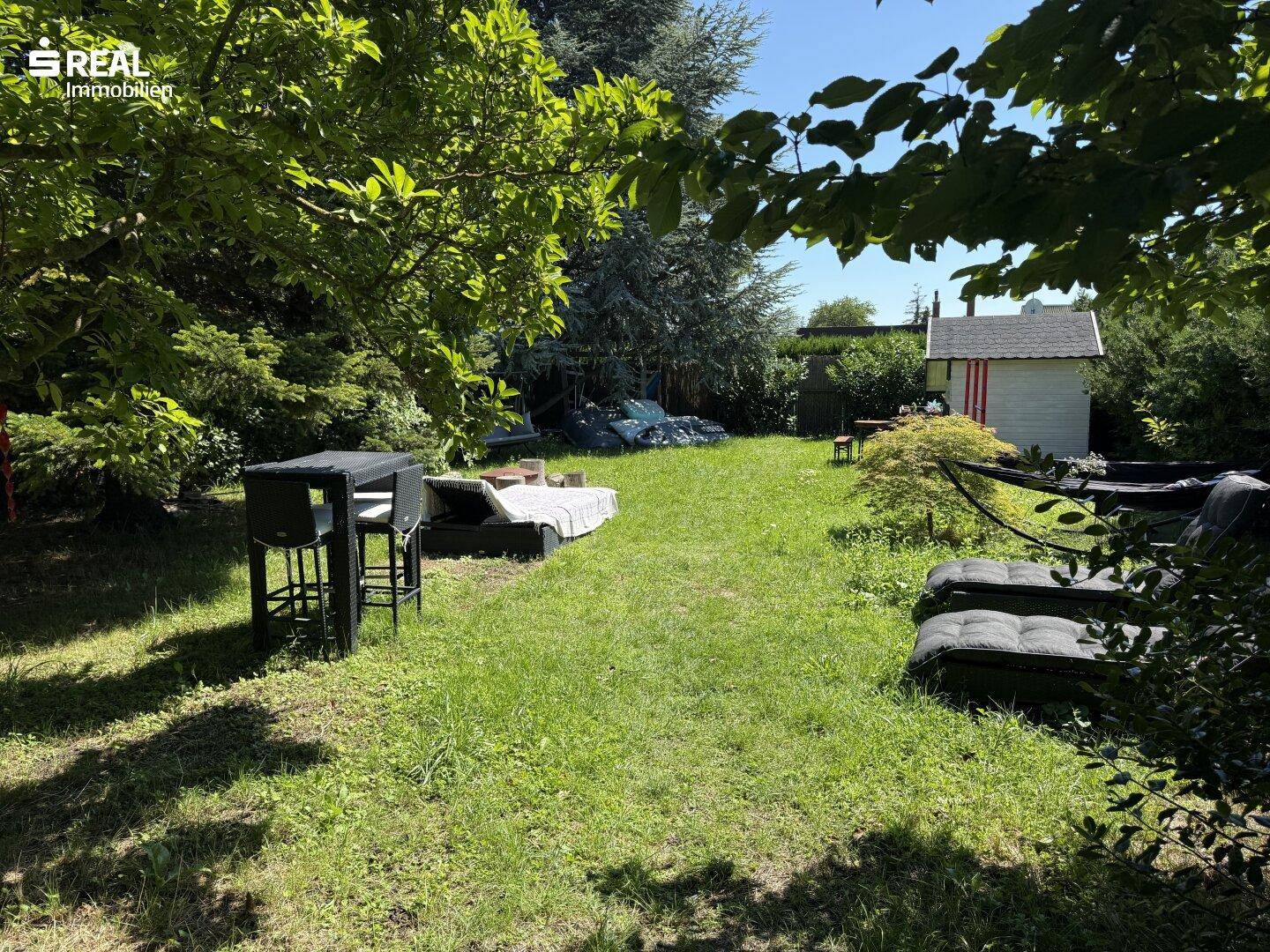 Großer Gartenbereich mit Outdoor-Lounge-Möbeln, Bartisch und alten Bäumen, perfekt zum Entspannen.