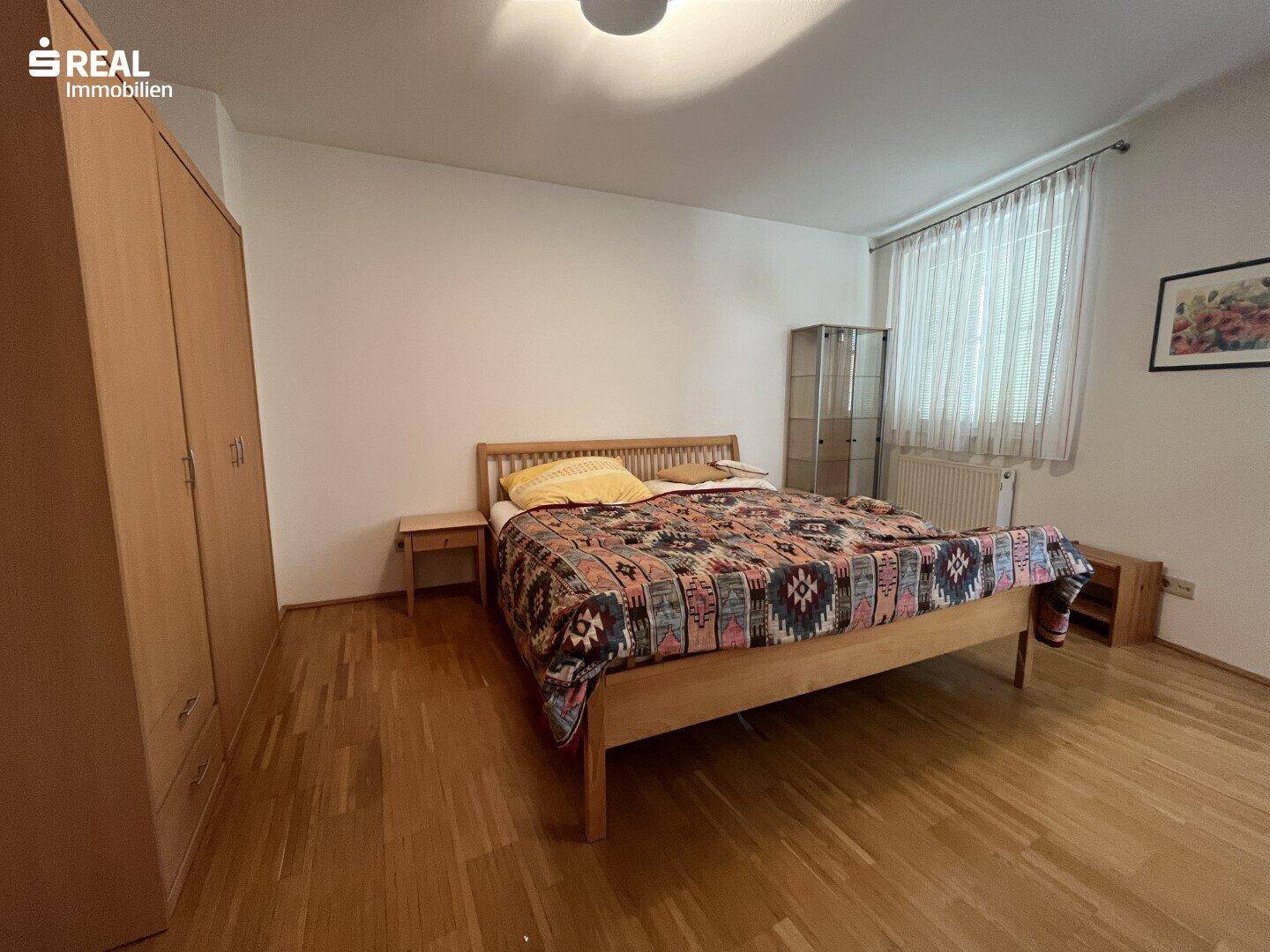 Gemütliches Schlafzimmer mit Holzbett, Kleiderschrank und warmem Parkettboden.