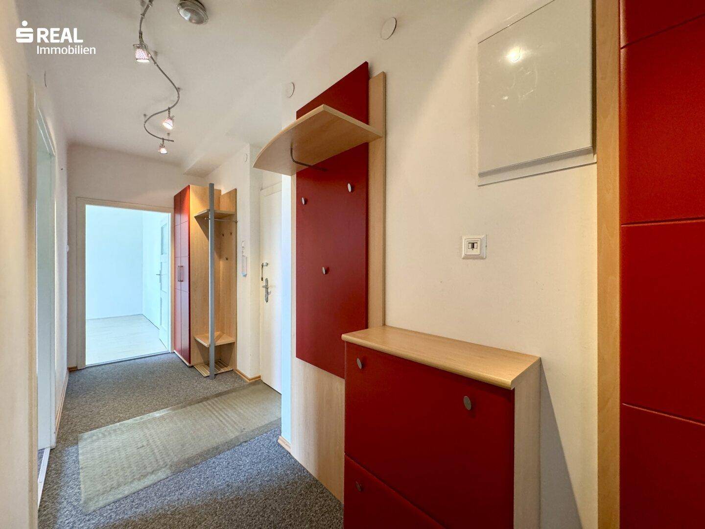 Eingangsbereich mit praktischer Garderobe in Rot und Holz, bietet Stauraum und Zugang zu Zimmern.