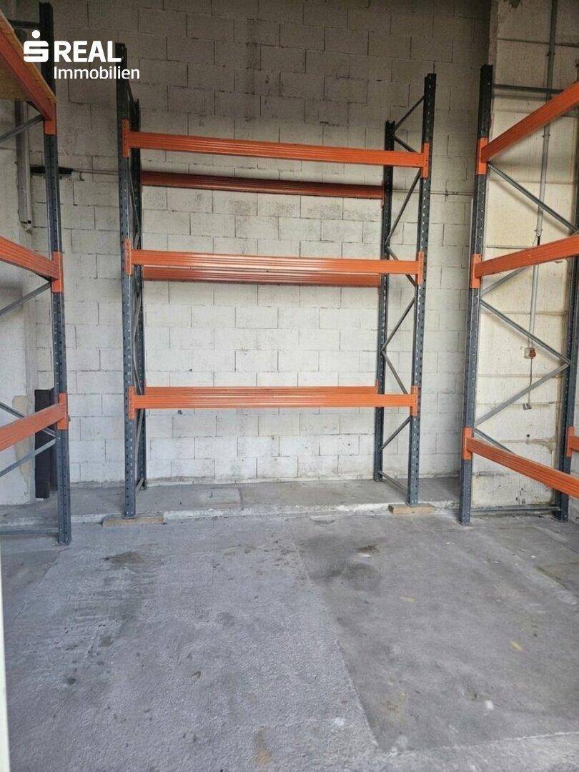 Weitere industrielle Regale vor einer Betonblockwand in einem Lagerbereich.