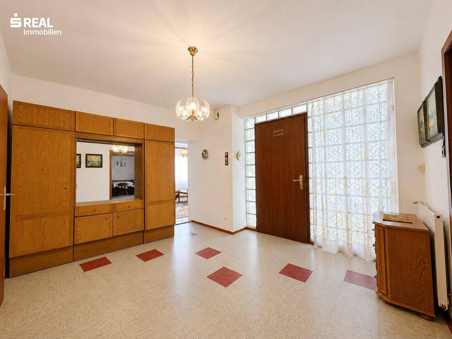 Heller Eingangsbereich mit großem Holzschrank und einer Glasbausteinwand für natürliches Licht.