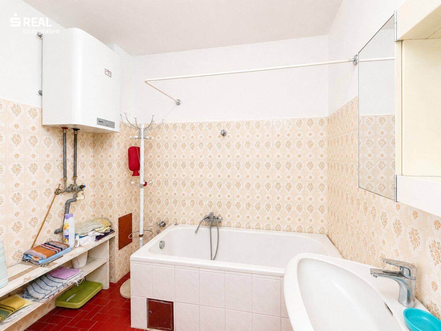 Badezimmer mit Badewanne, Waschbecken und traditionellen Fliesen in Pastellfarben.