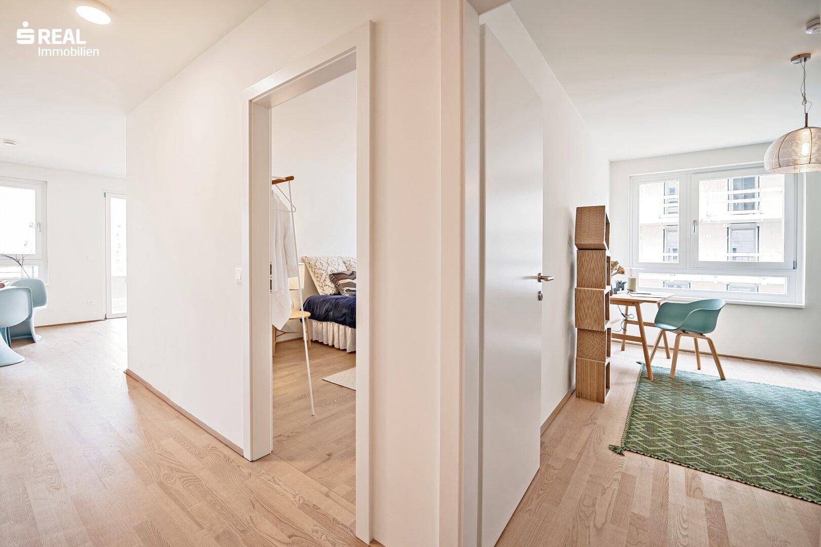 Heller Flur mit Holzboden, der zu den verschiedenen Zimmern der Wohnung führt.