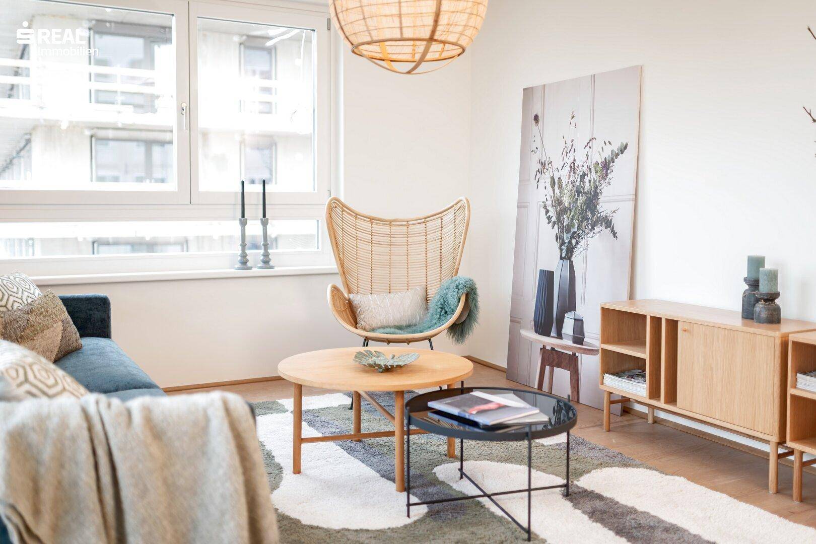 Gemütliches Wohnzimmer mit bequemer Couch, Couchtischen und großem Fenster.