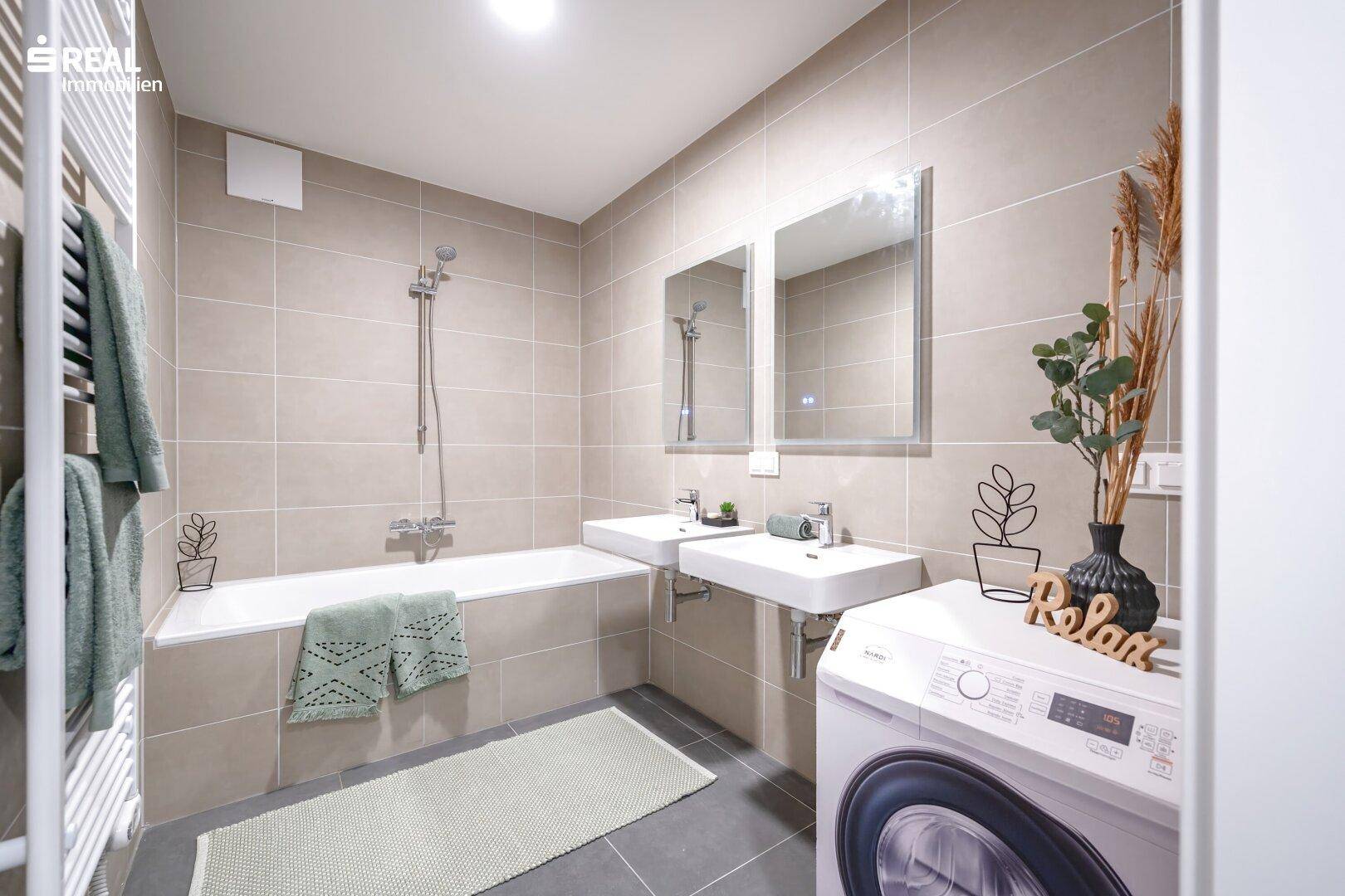 Modernes Badezimmer mit Badewanne, Doppelwaschbecken und Waschmaschine, funktional und stilvoll gestaltet.