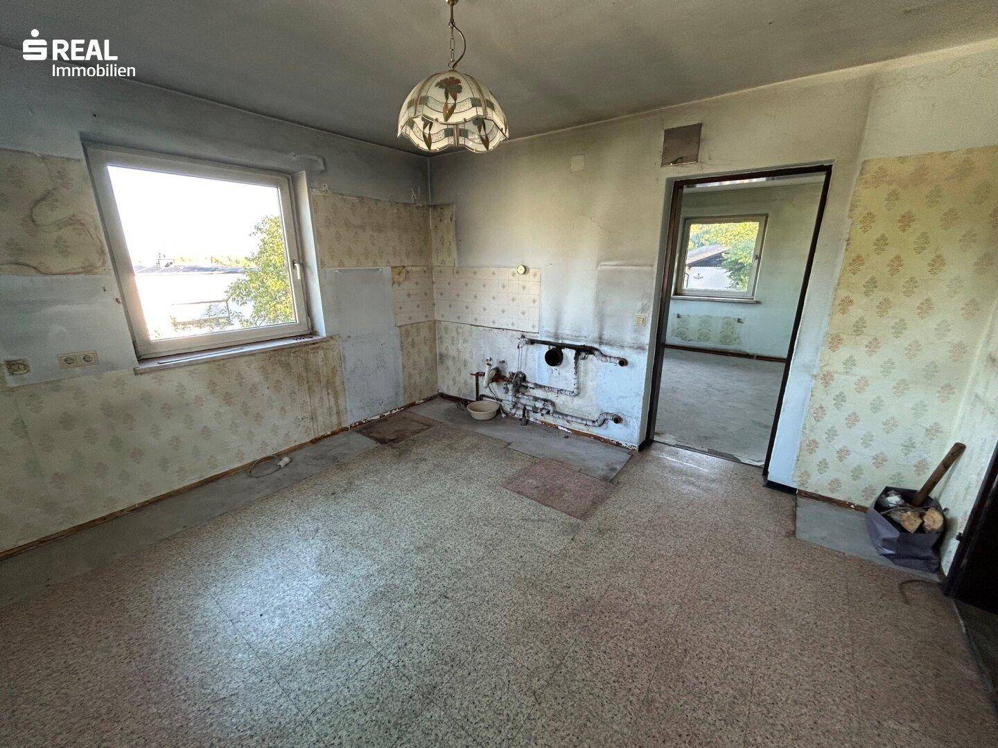 Küche in Renovierung mit sichtbaren Installationen und Blick in einen weiteren Raum.