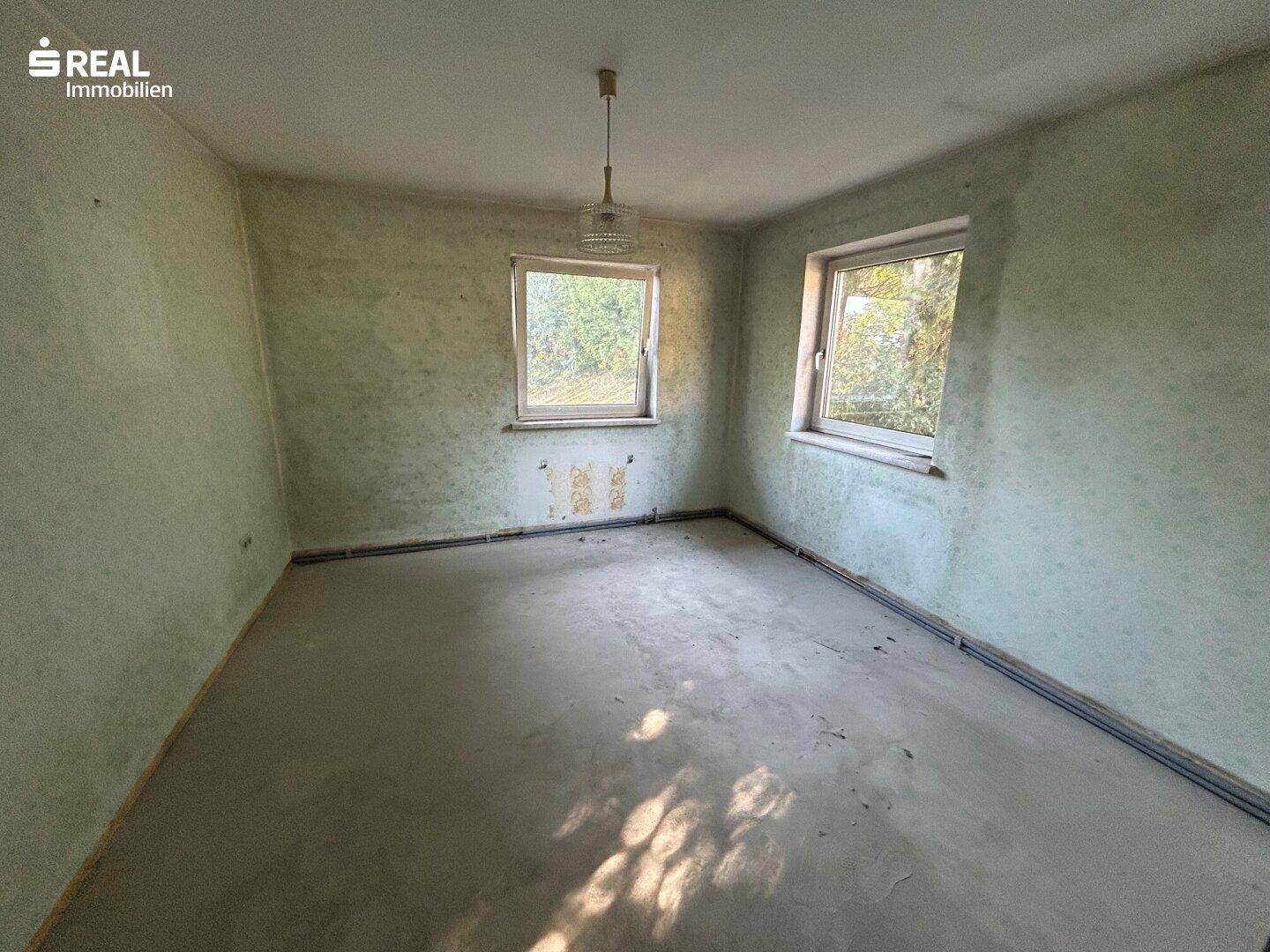 Weiteres Zimmer in Renovierung mit zwei Fenstern und vorbereitetem Boden.