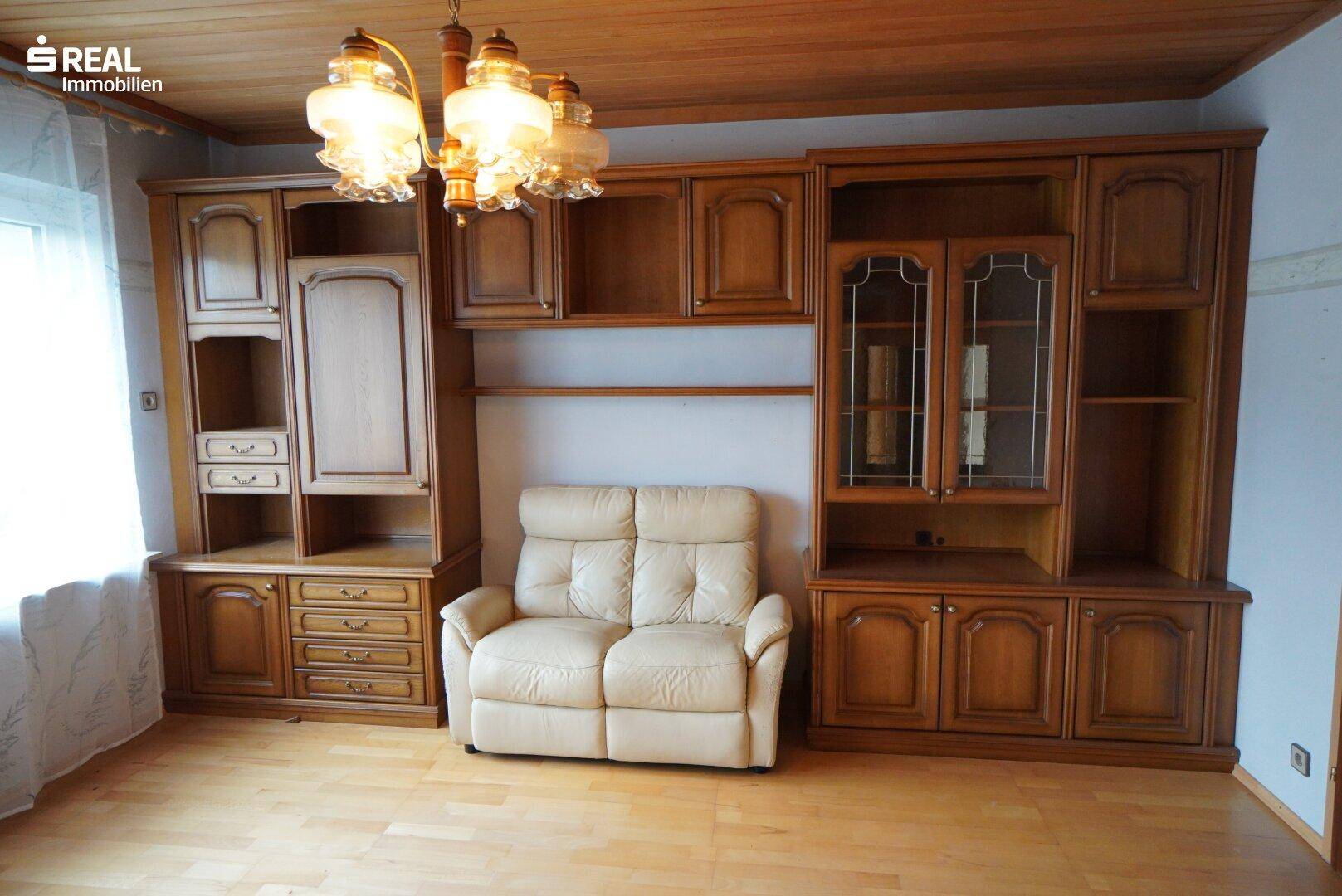 Wohnzimmer mit Holzdecke, Parkettboden und traditionellen Holzmöbeln.
