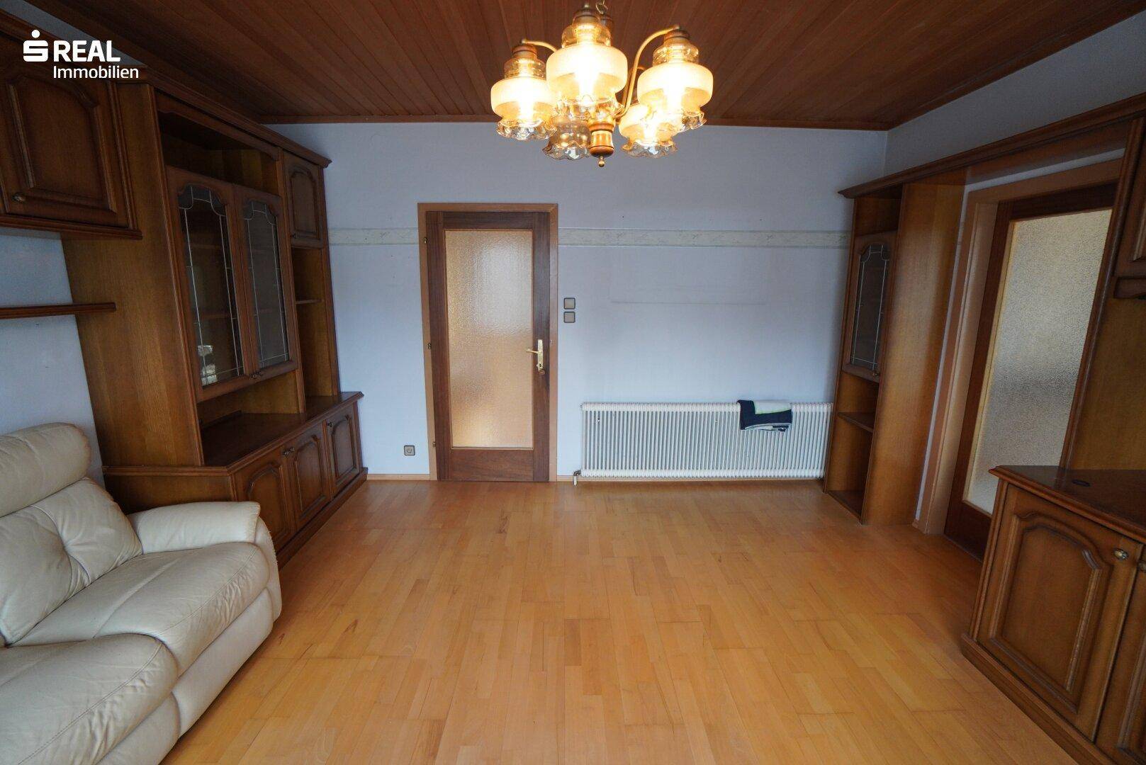 Geräumiges Wohnzimmer mit Parkettboden, Holzdecke und traditioneller Einrichtung.
