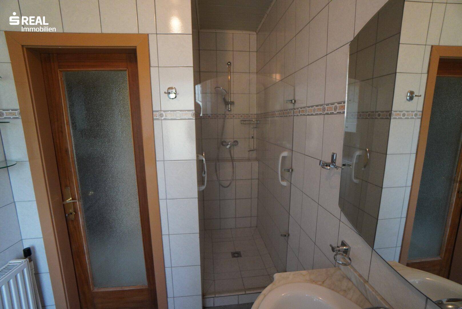 Badezimmer mit Duschkabine, Waschbecken und Fliesen in hellem Design.