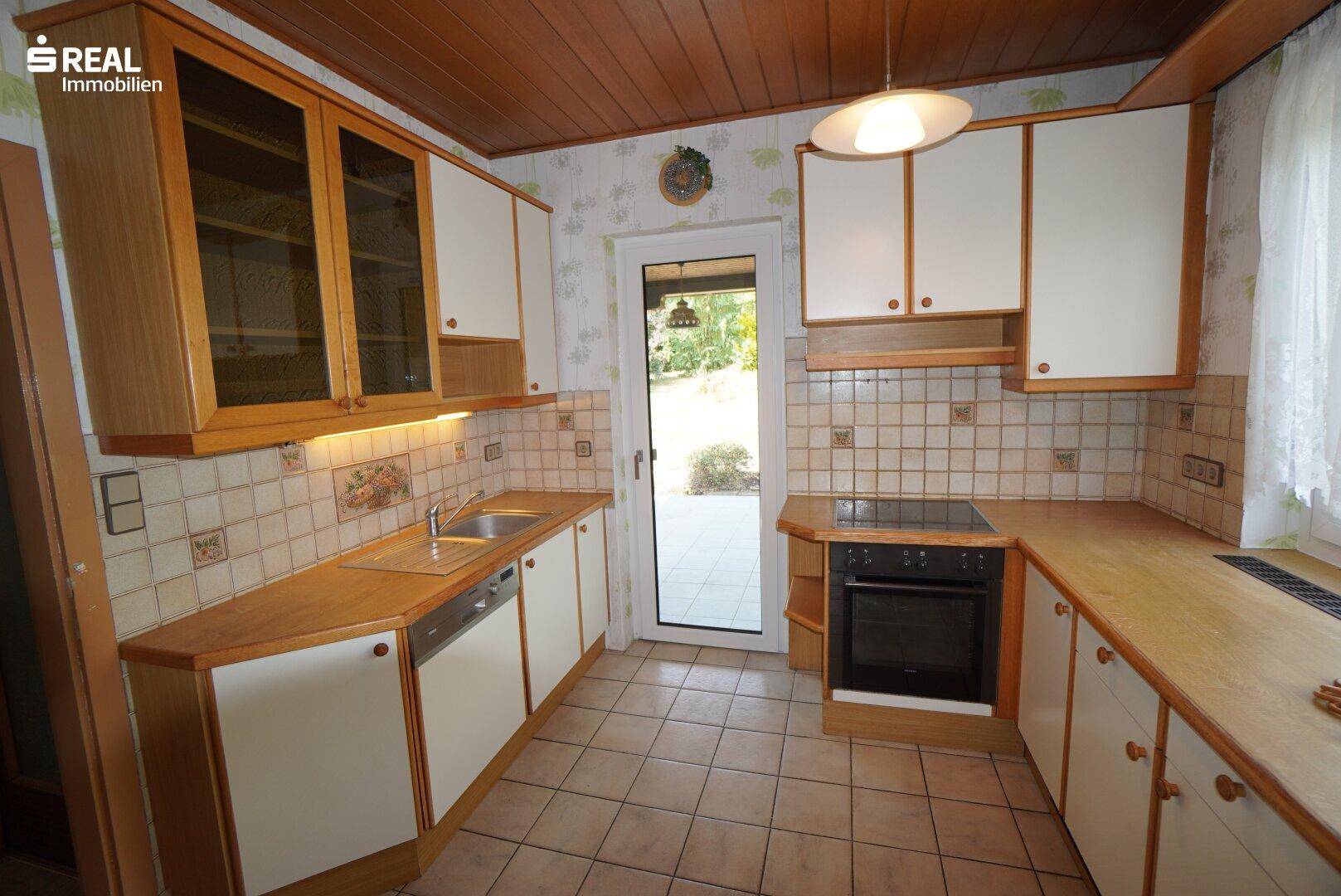 Traditionelle Küche mit Holzdecke, Fliesenboden und direktem Zugang zum Garten.