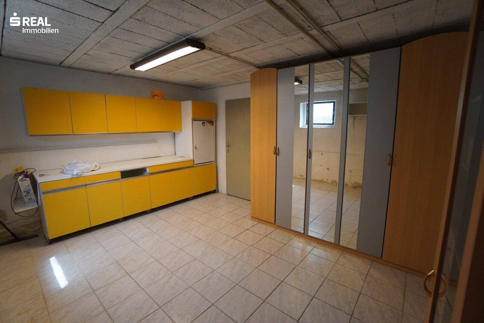 Geräumiger Kellerraum mit gelben Schränken, Fliesenboden und Spiegelschränken für Stauraum.