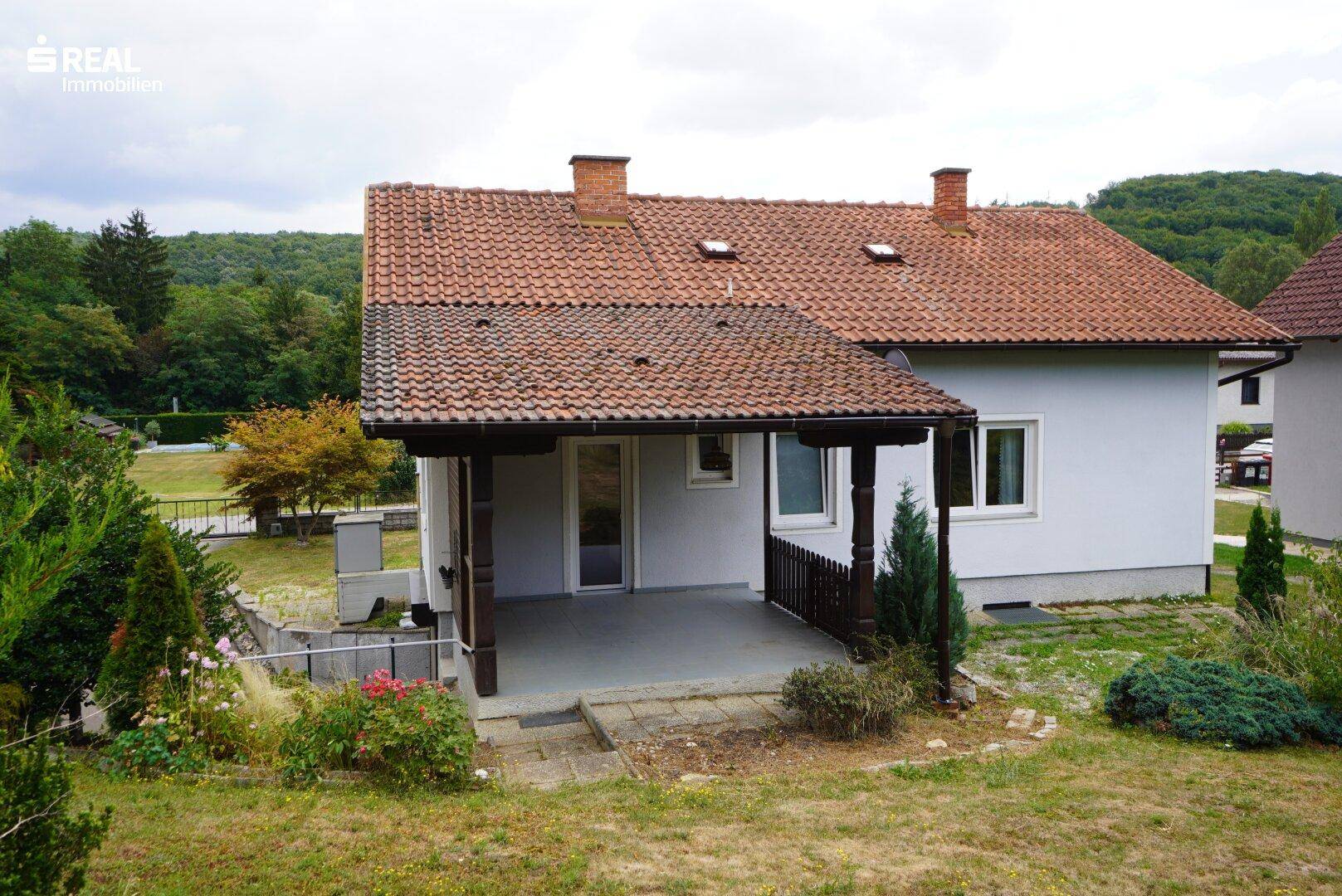 Überdachte Terrasse am Haus mit Blick auf den Garten und die umliegende Landschaft.