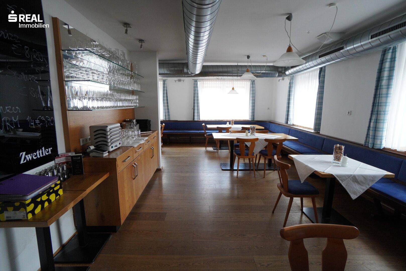 Geräumiger Gastraum mit Bar, Glasregalen und Sitzgelegenheiten für Gäste.