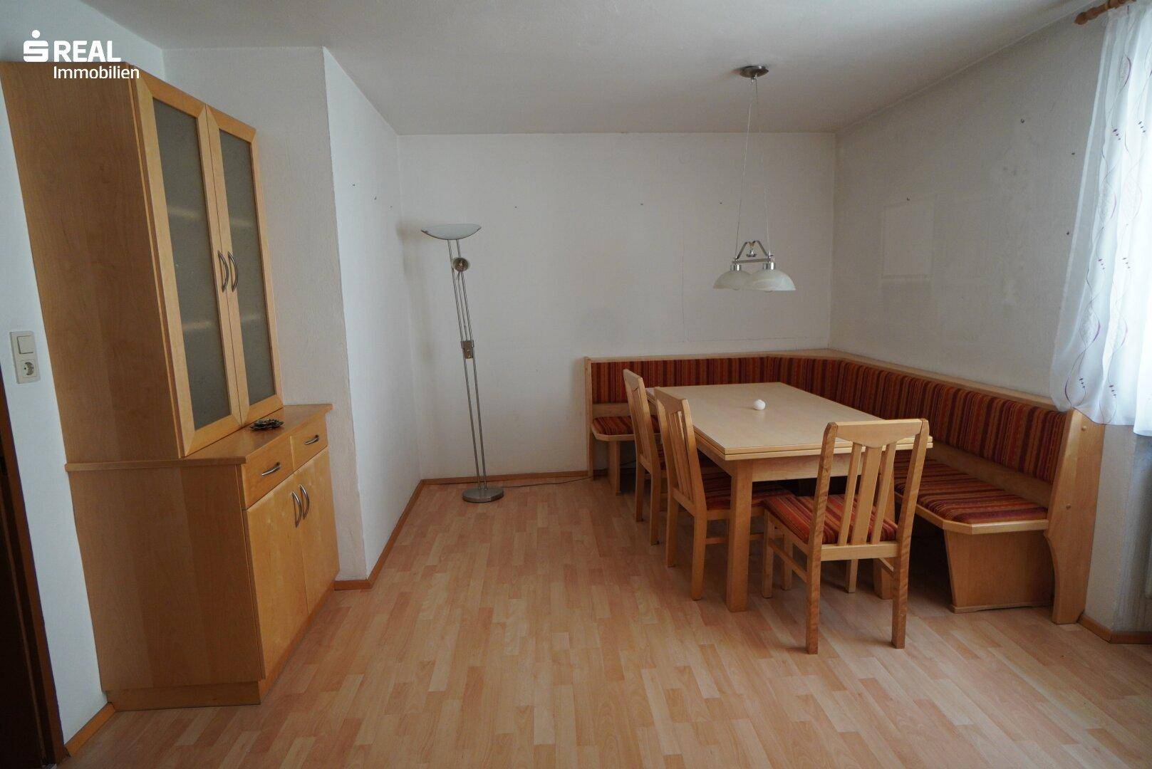 Gemütlicher Essbereich mit Eckbank, Holztisch und passendem Schrank auf Laminatboden.