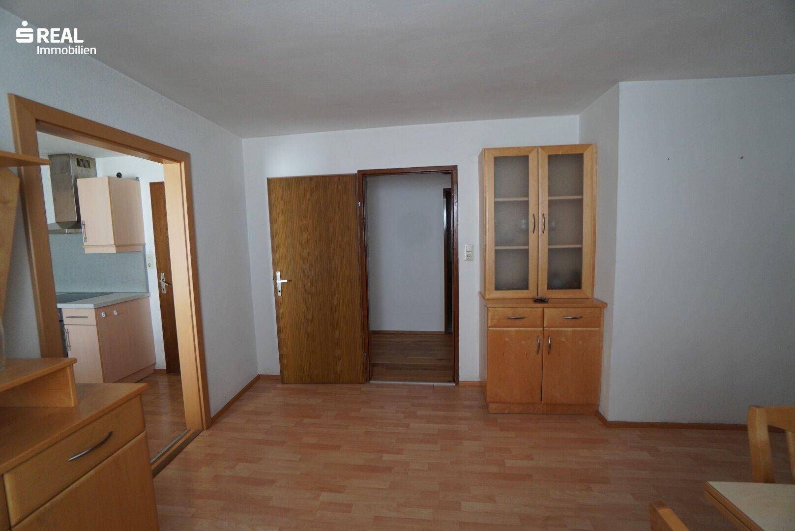 Heller Flur mit Laminatboden und Holztüren, der in die Küche führt.