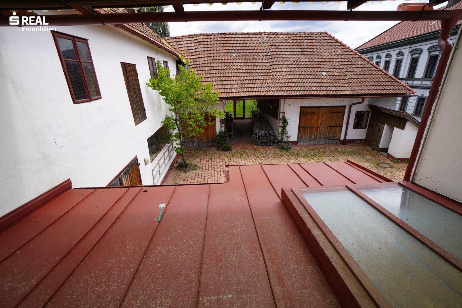Blick von oben auf einen Innenhof mit traditionellen Gebäuden und Ziegeldächern.