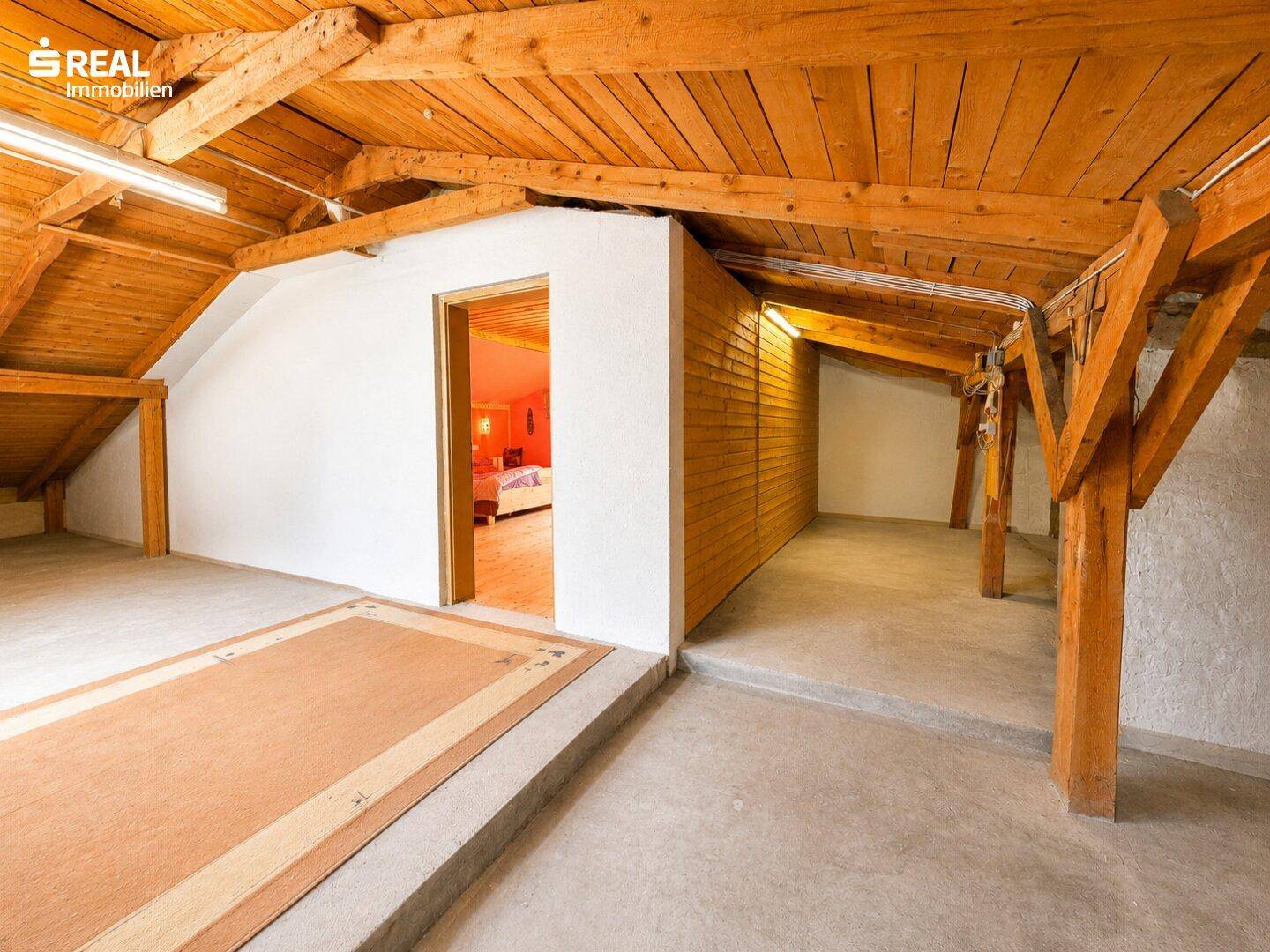 Geräumiger Dachboden mit sichtbaren Holzbalken und Betonboden, bietet viel Stauraum.