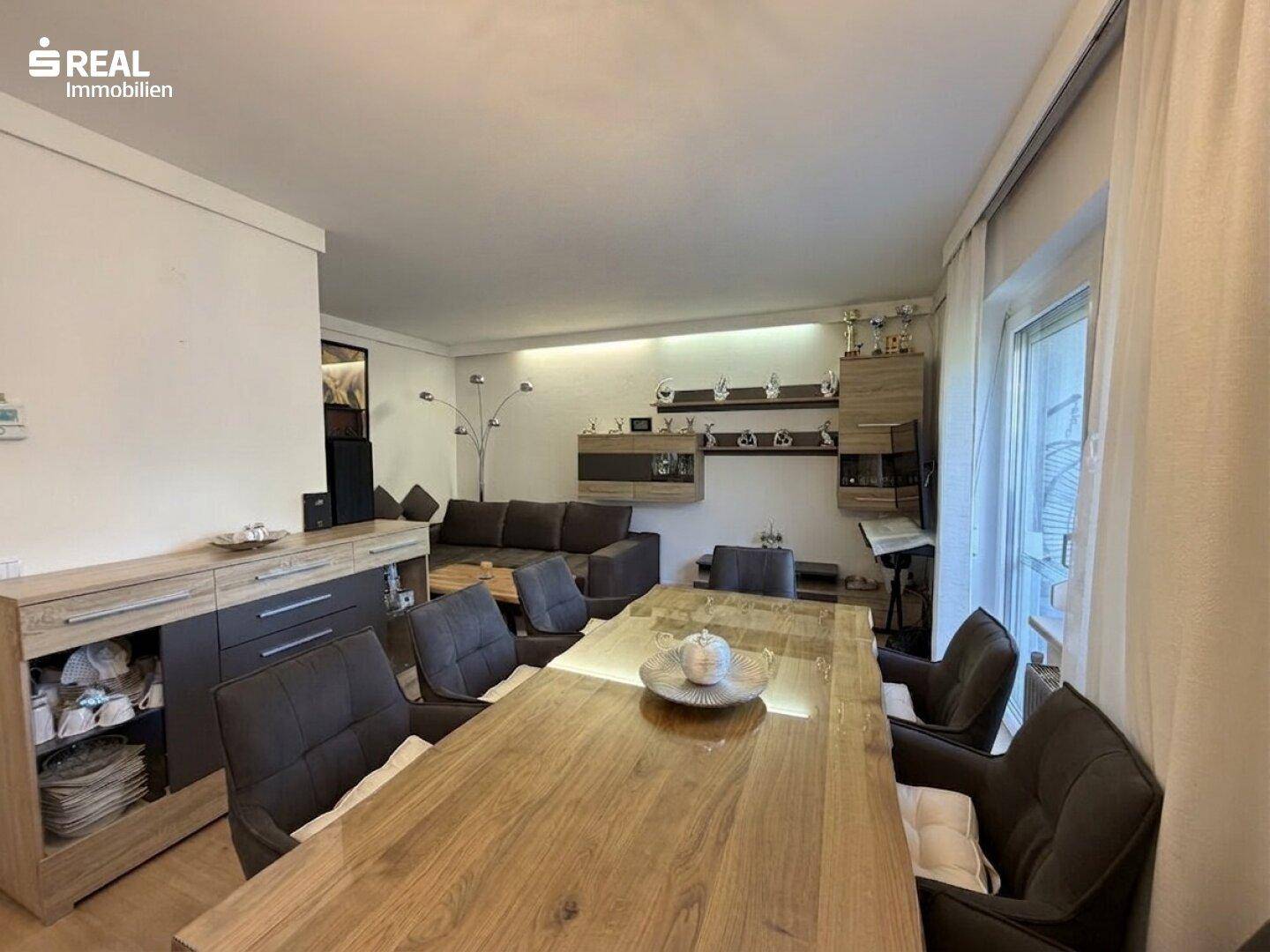 Geräumiger Wohn-Essbereich mit großem Holztisch, Sofa und modernen Möbeln.
