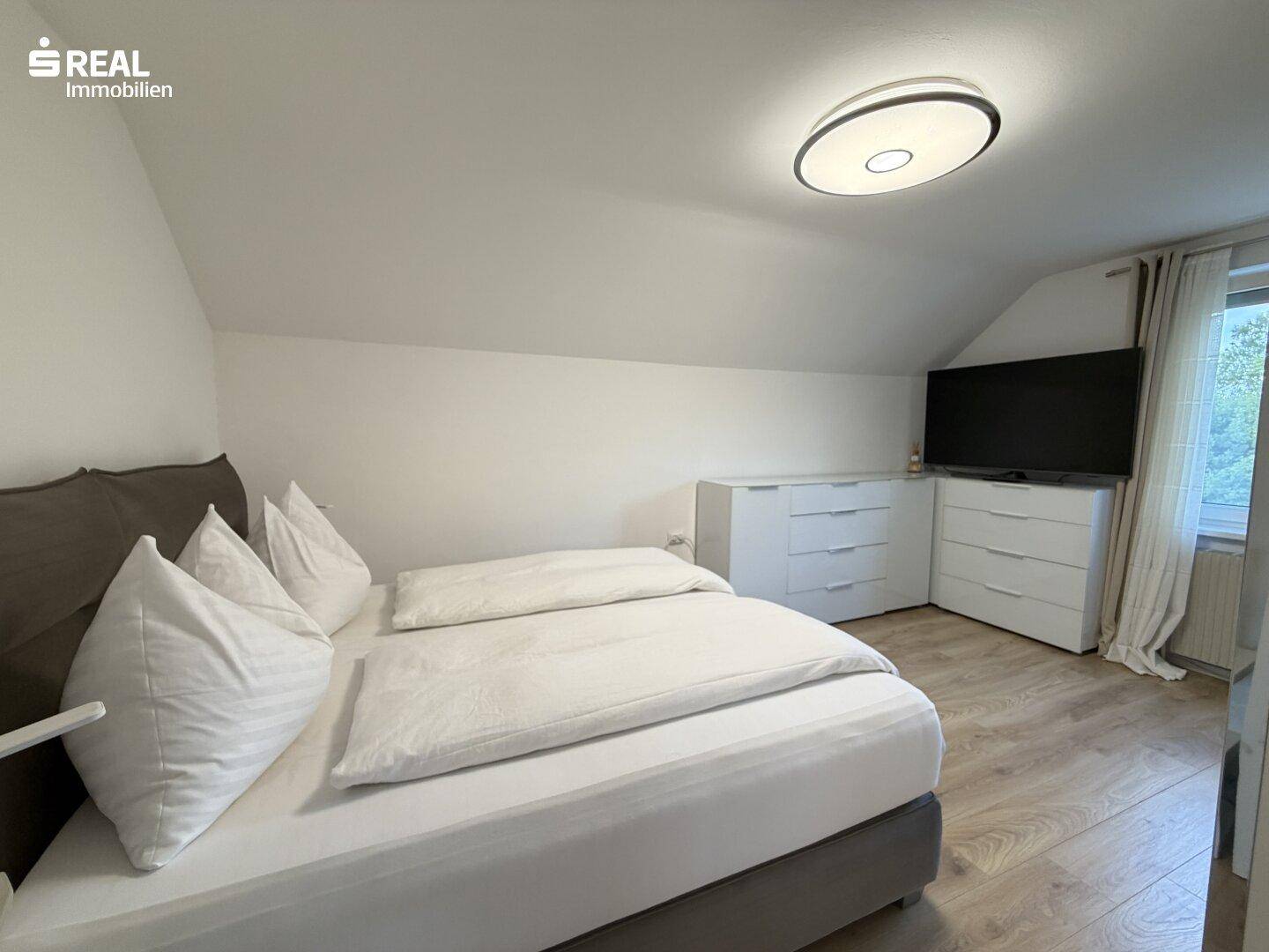 Schlafzimmer mit Dachschräge, Doppelbett und Kommoden.