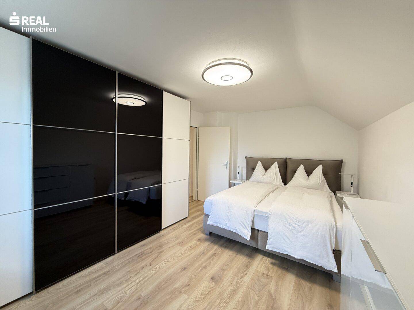 Schlafzimmer mit großem Schiebetürenschrank und Doppelbett.