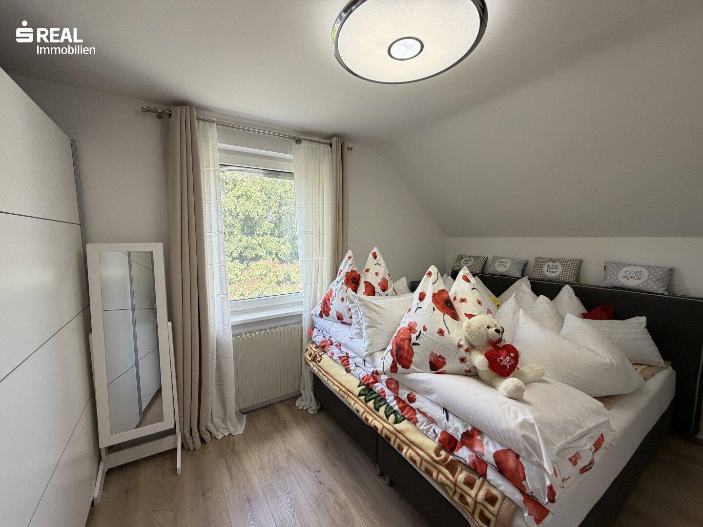 Schlafzimmer mit Fenster, Bett und Kleiderschrank.