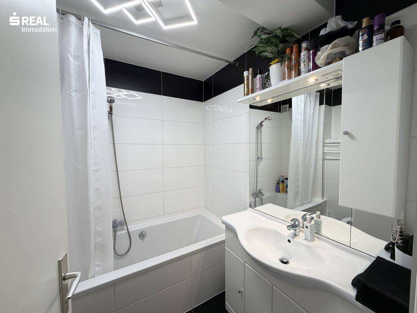 Badezimmer mit Badewanne, Waschbecken und Spiegelschrank.