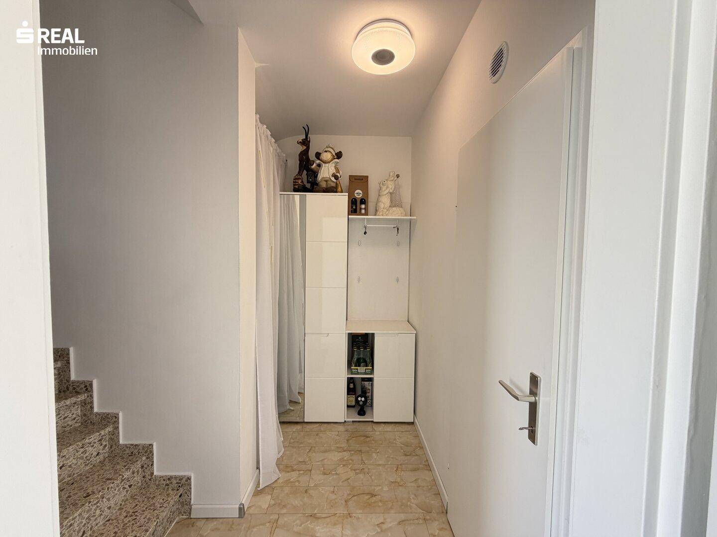 Eingangsbereich mit Treppe und Fliesenboden.