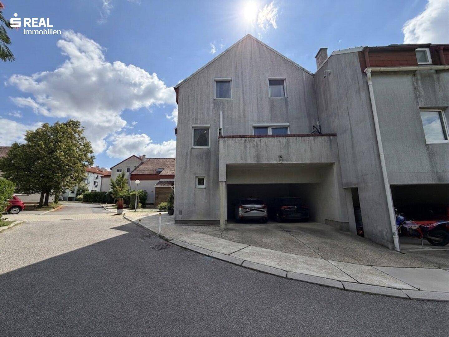 Mehrfamilienhaus mit Garagenzufahrt und Parkmöglichkeiten.