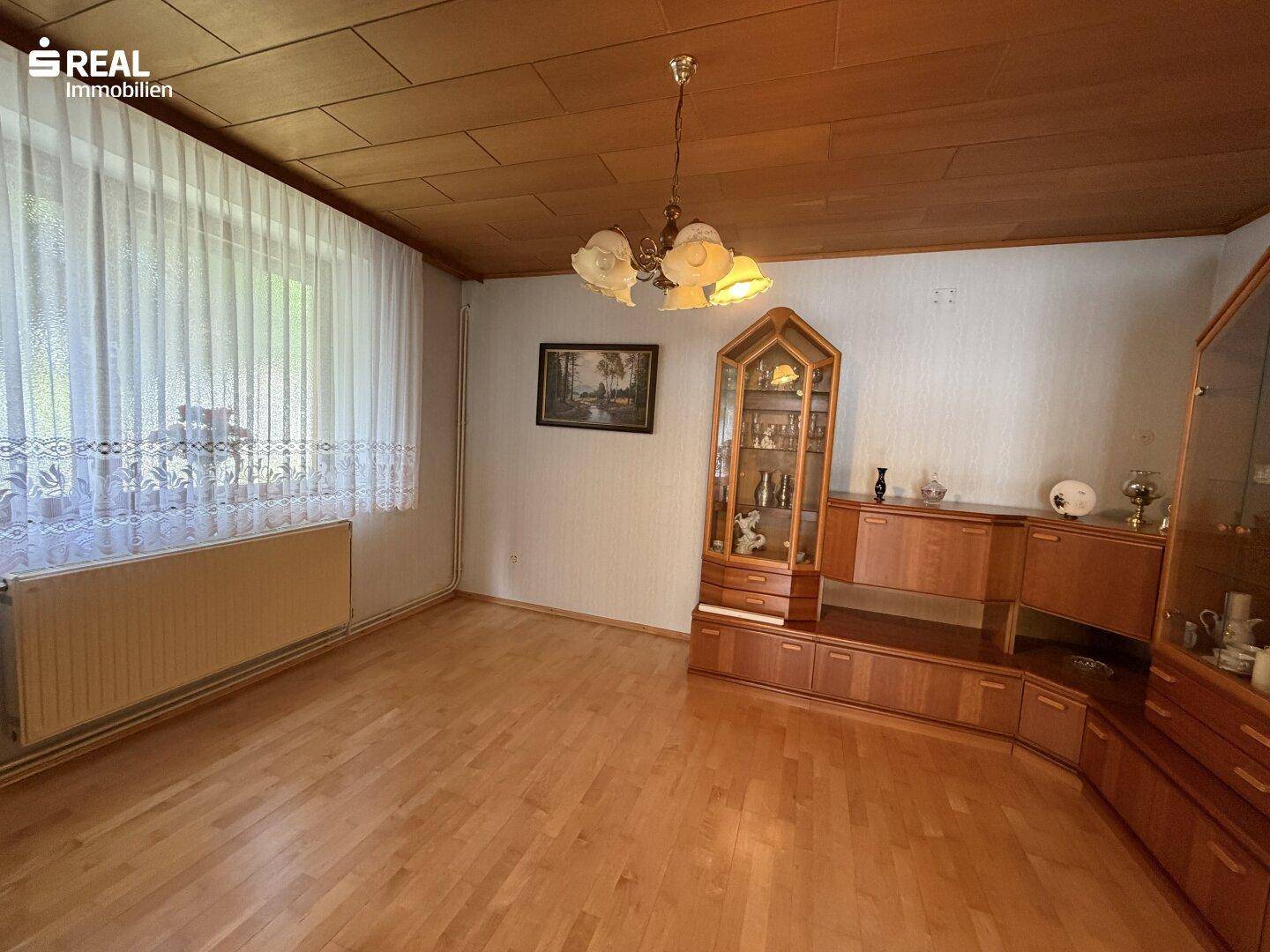 Gemütliches Wohnzimmer mit Holzparkett, Holzdecke und traditionellen Möbeln.