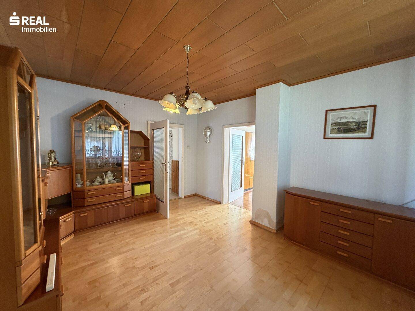 Wohnzimmer mit Holzboden, Holzdecke und traditionellen Schränken, offen zu weiteren Räumen.