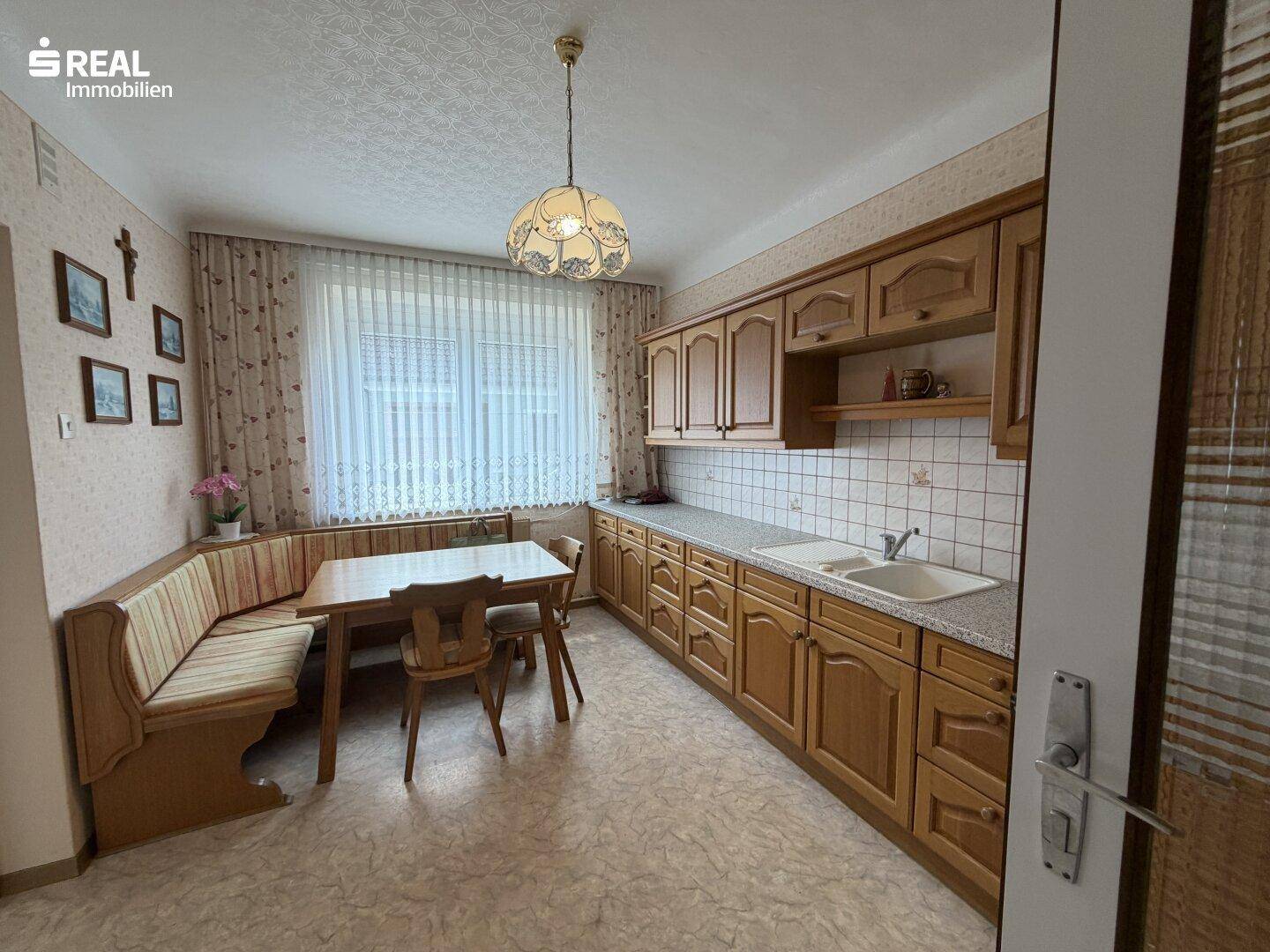 Traditionelle Wohnküche mit Holzeinbauten, Essbereich und Fenster.