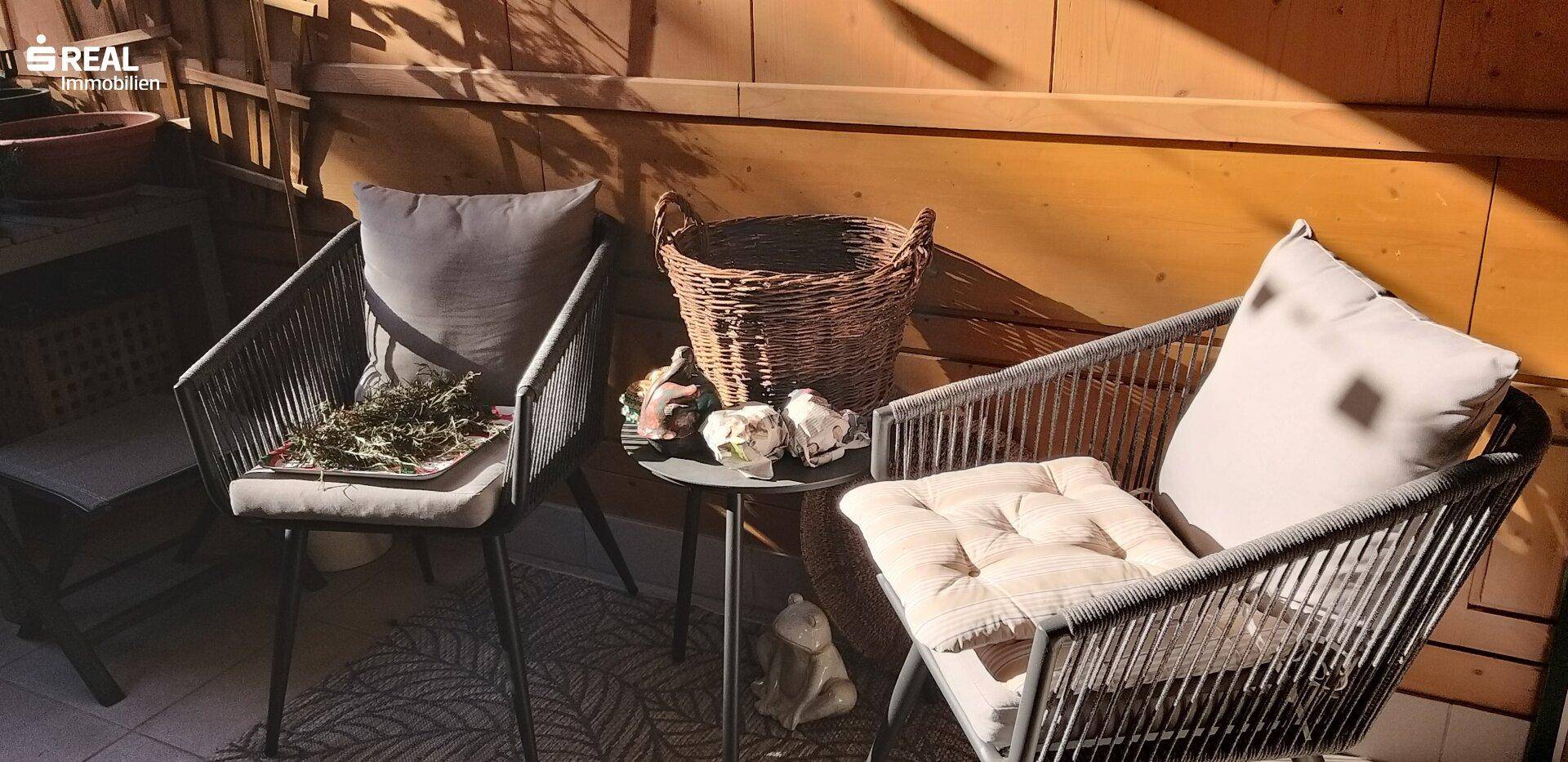 Gemütlicher Balkon mit bequemen Sitzgelegenheiten, einem Beistelltisch und Holzwänden.