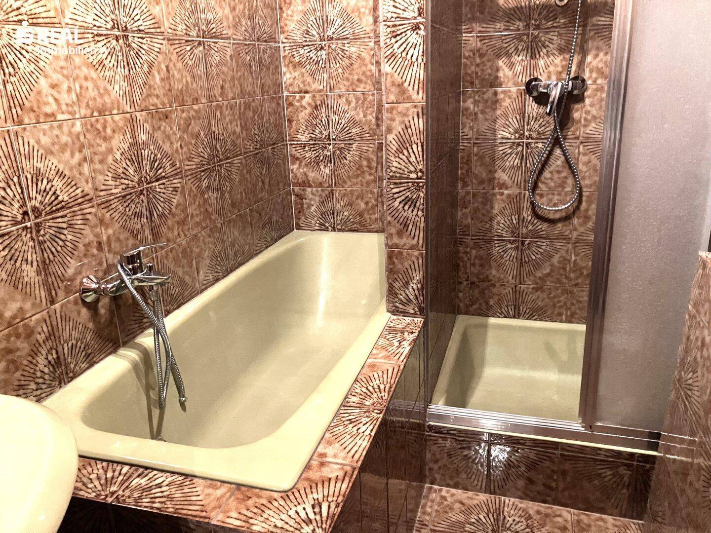 Badezimmer mit braunen Fliesen, Badewanne und separater Dusche.