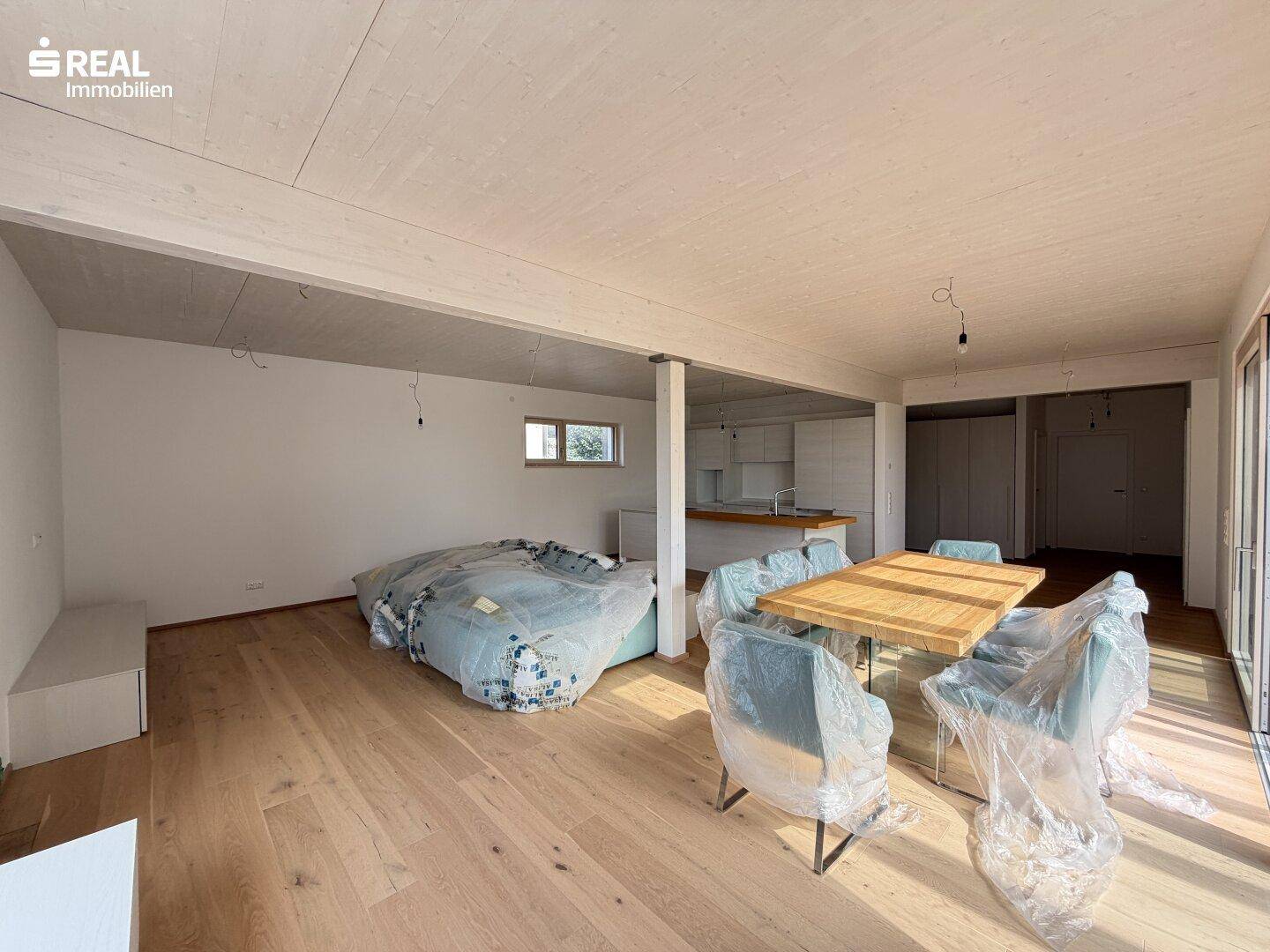 Geräumiger offener Wohnbereich mit Holzboden, Essbereich und Blick auf die moderne Küche.