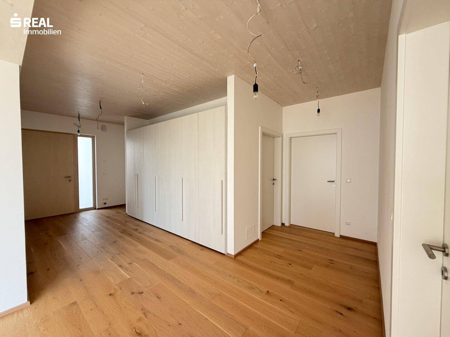 Heller Flur mit Holzboden und integrierten weißen Einbauschränken, bietet viel Stauraum.