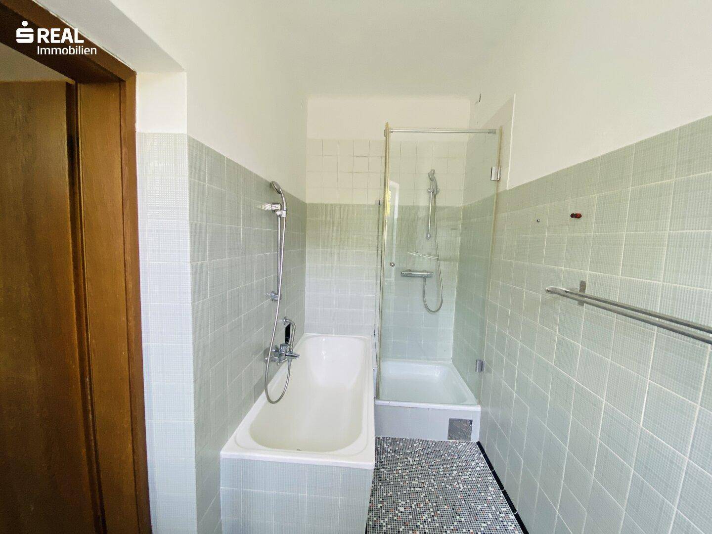 Badezimmer mit Badewanne, separater Dusche und hellgrünen Fliesen an den Wänden.