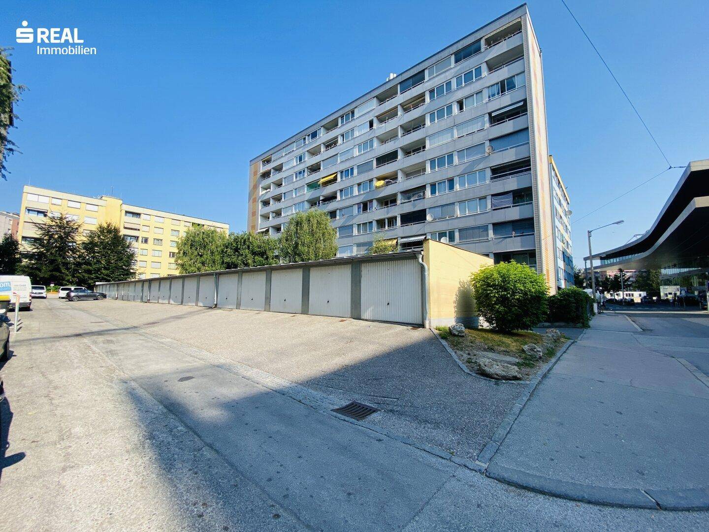 Gesamtansicht der Garagenanlage vor einem großen Mehrfamilienhaus mit vielen Balkonen.