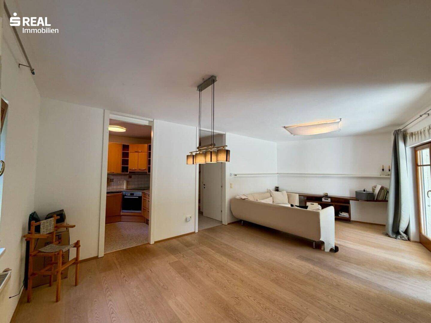 Offener Wohnbereich mit Holzboden und Blick in die angrenzende Küche.