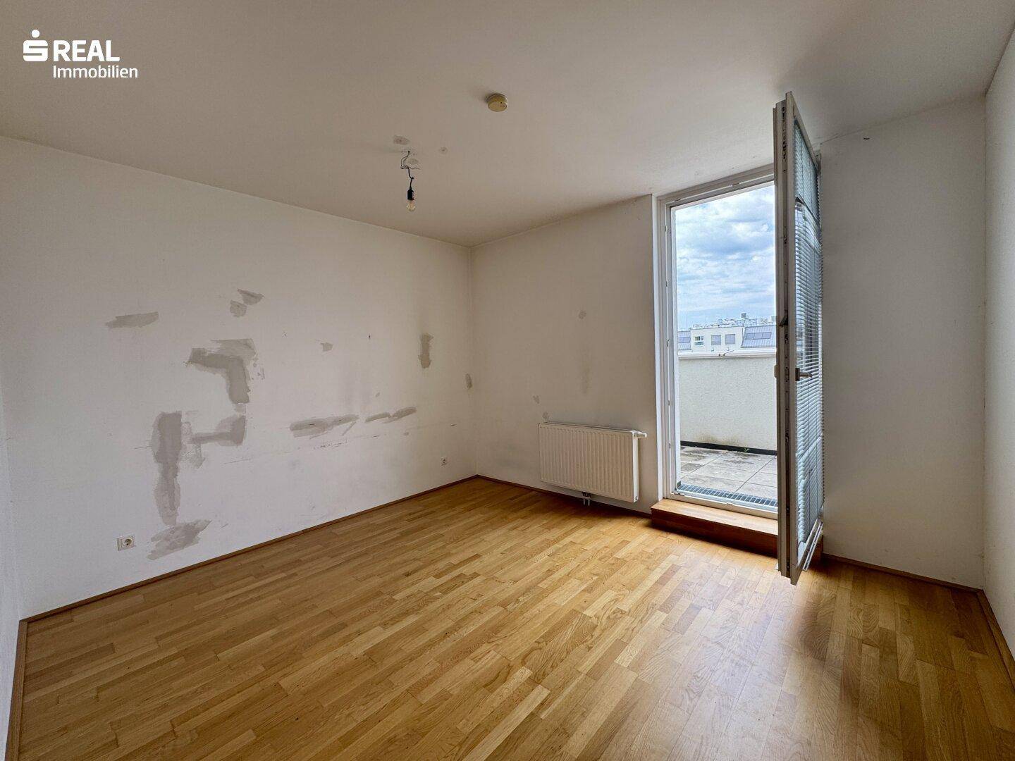 Zimmer mit Holzboden und Zugang zu einem Außenbereich, ideal für frische Luft.