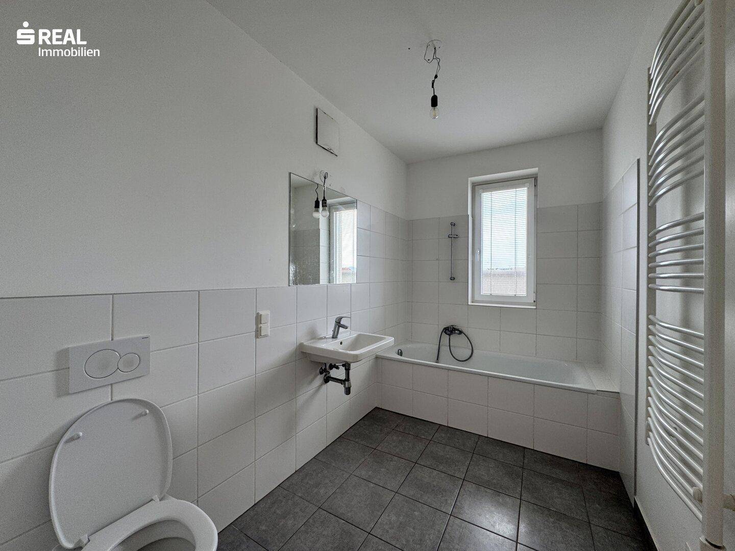 Badezimmer mit Badewanne, WC, Waschbecken und einem beheizten Handtuchhalter.