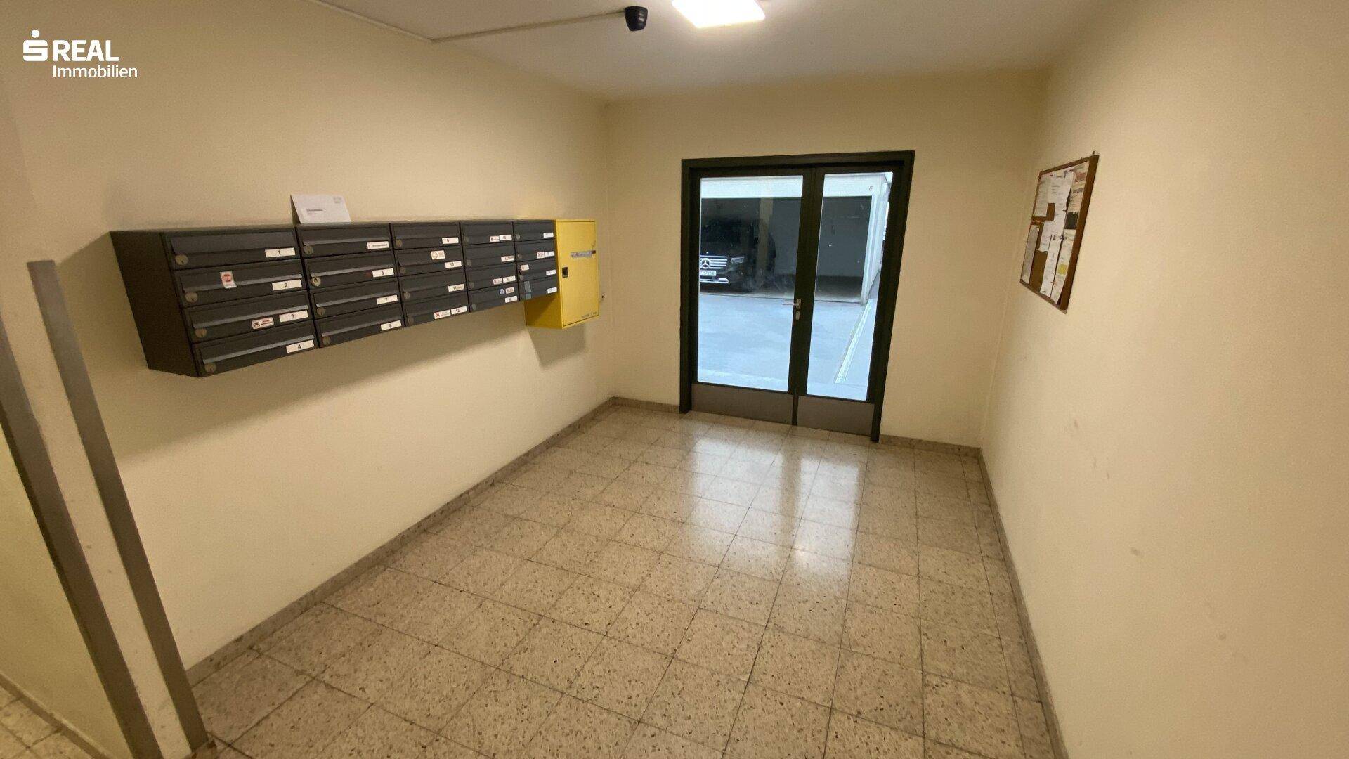 Heller Eingangsbereich des Gebäudes mit Briefkästen und gefliestem Boden, führt zum Treppenhaus.