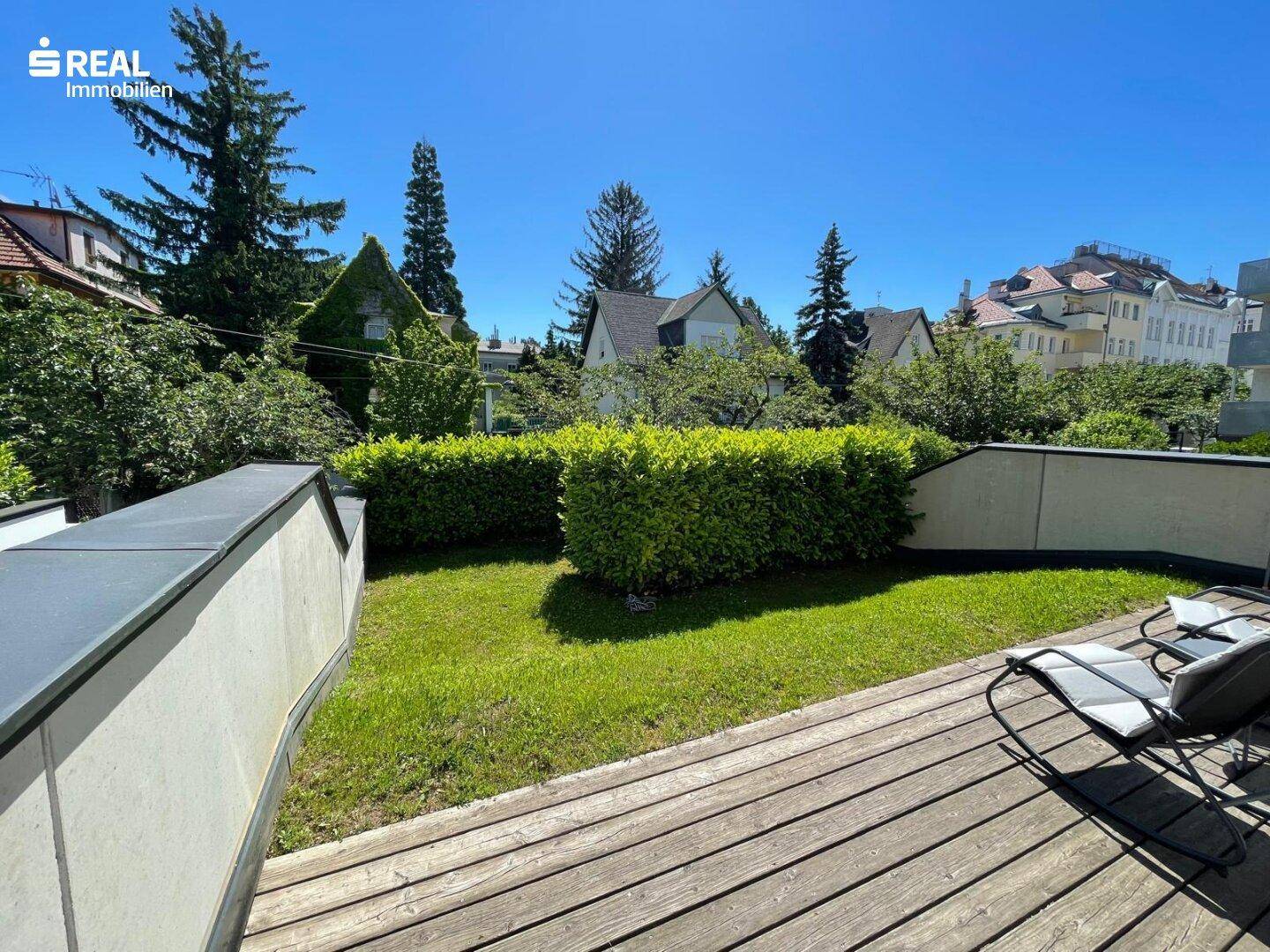 Weitläufige Rasenfläche auf einer Holzterrasse mit Blick auf die umliegende grüne Landschaft.