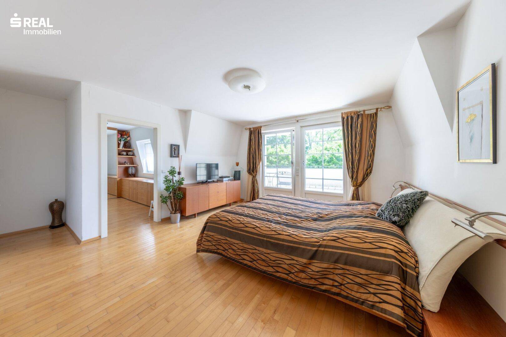 Geräumiges Schlafzimmer mit Holzboden und Zugang zu einem weiteren Raum, hell und einladend.