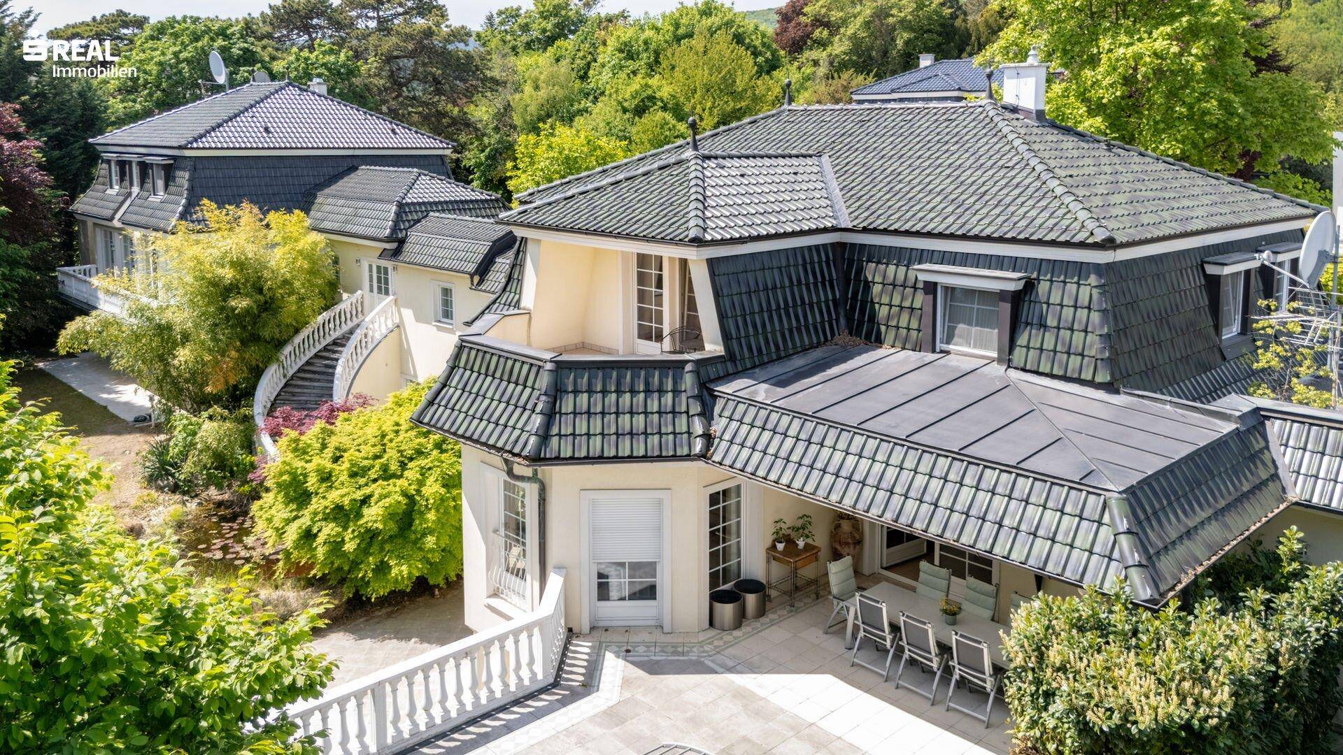 Panoramablick auf die elegante Villa mit ihren Terrassen und dem weitläufigen Grundstück.