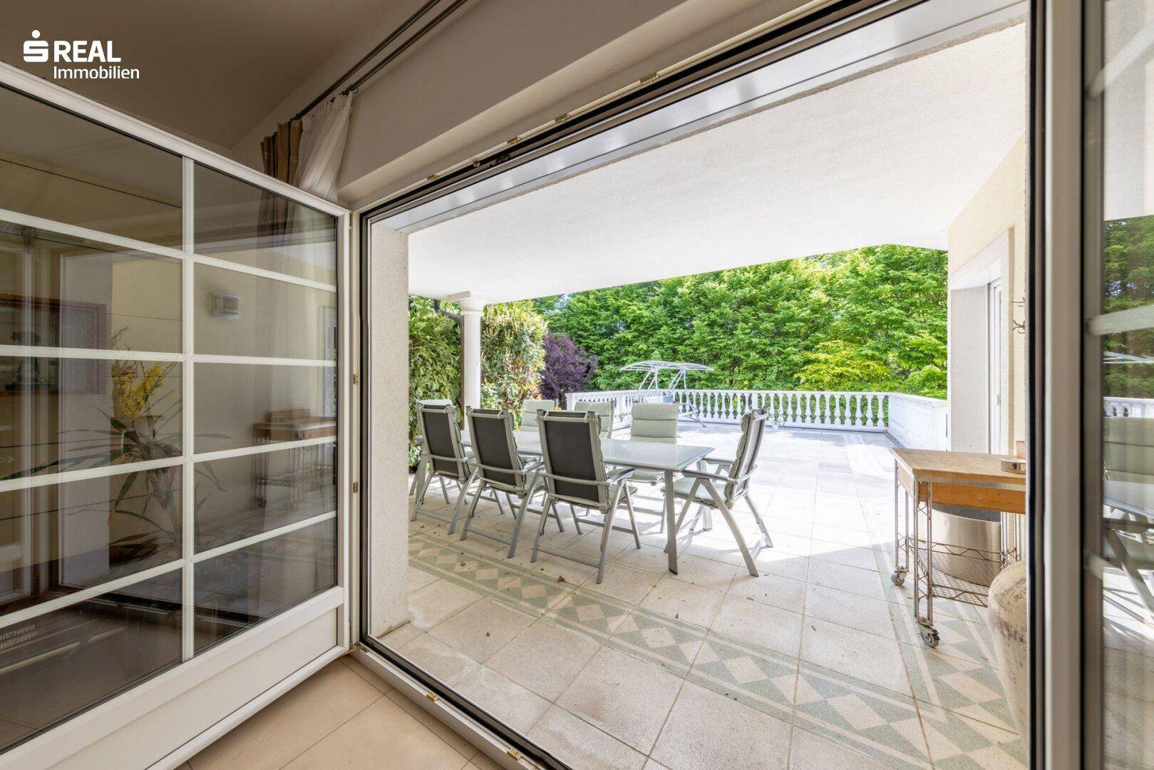 Überdachte Terrasse mit Esstisch und Blick ins Grüne, ideal für Mahlzeiten im Freien.