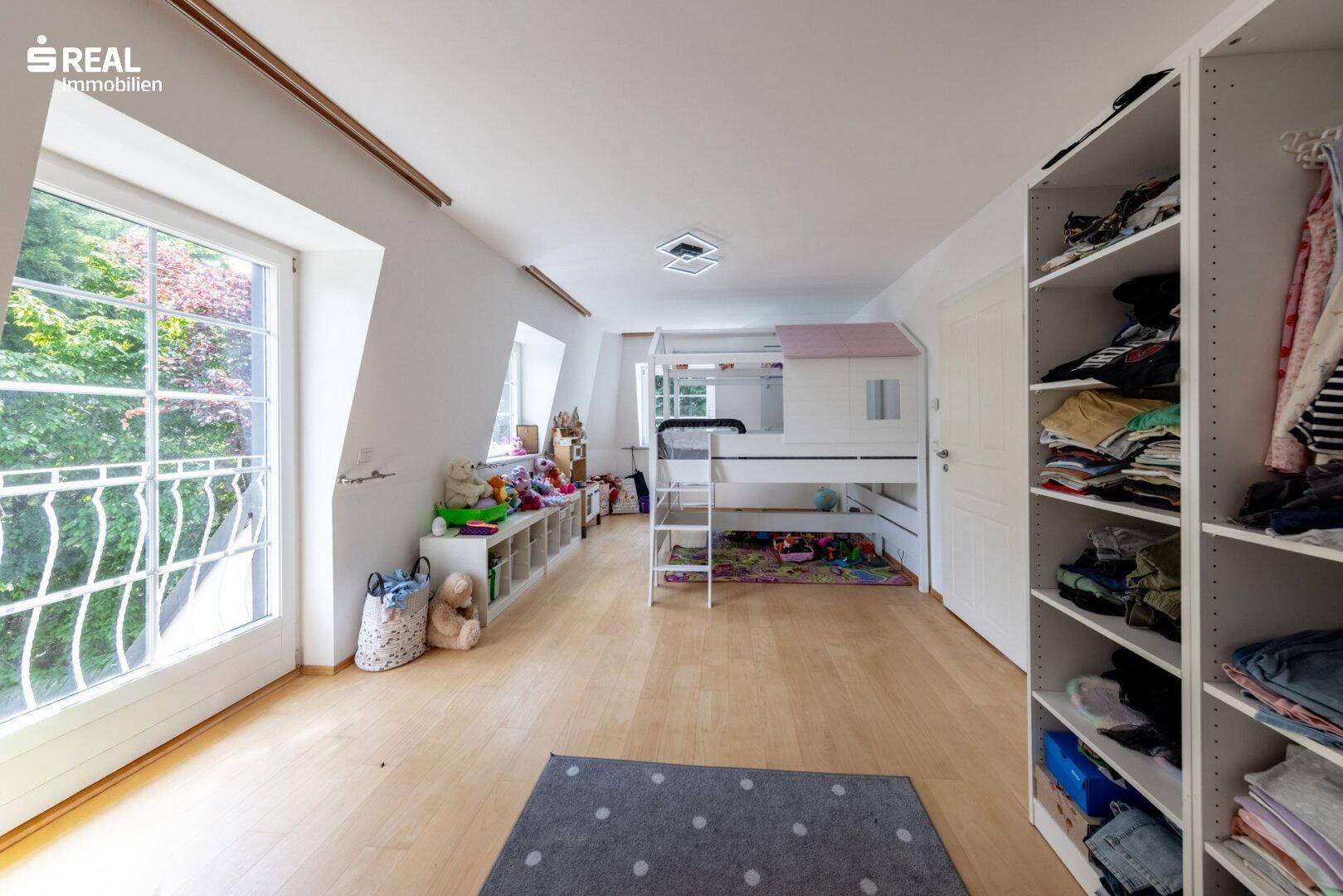 Kinderzimmer mit Hochbett, Holzboden und Zugang zu einem französischen Balkon.