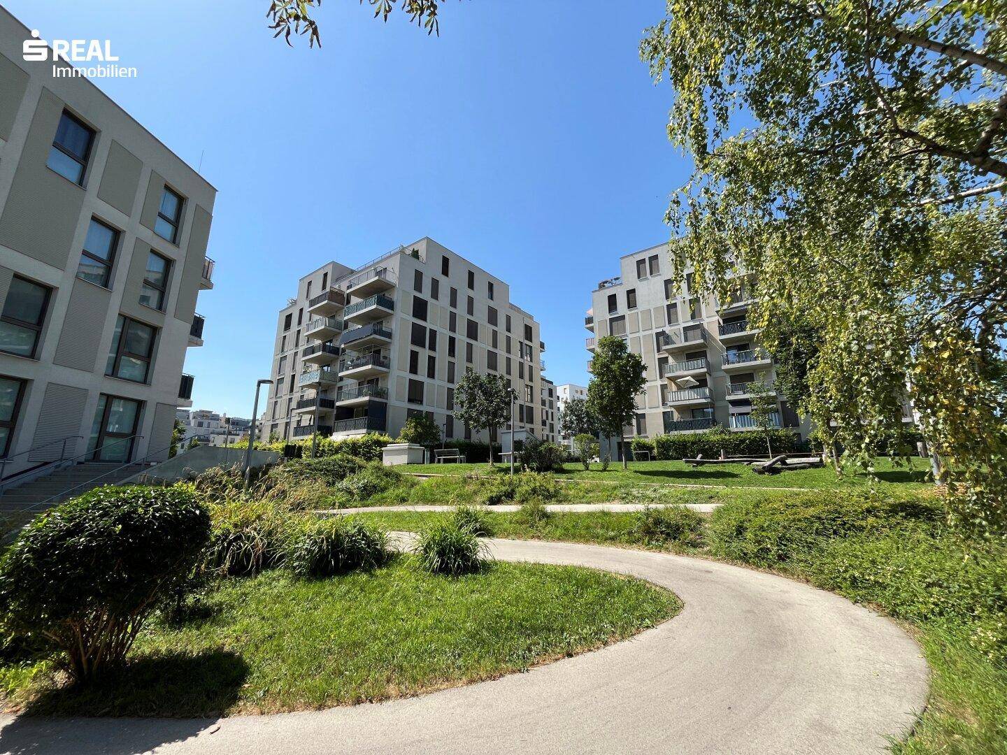 Moderne Wohngebäude umgeben von gepflegten Grünflächen und Bäumen.